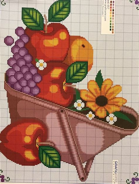 A Cross Stitch Pattern With Fruit And Flowers In A Wheelbarrow On A