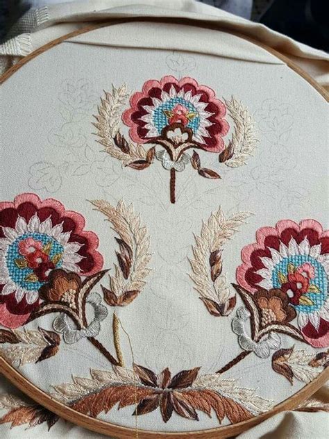 A Close Up Of A Embroidery On A Piece Of Cloth With Flowers In The Middle