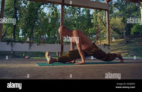 Bald Barefooted Yogi With Naked Torso Performs Asanas On The Wooden