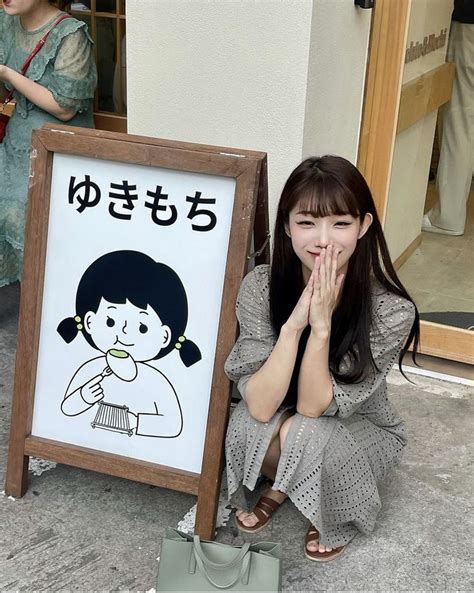 A Woman Sitting On The Ground Next To A Sign With A Drawing Of A Girl