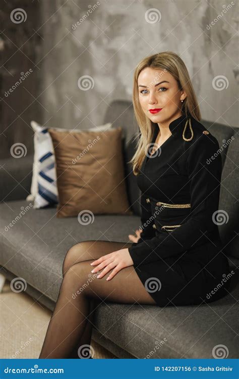 Elegant Woman Sitting On Sofa At Home Blond Hair Lady In Black Dress