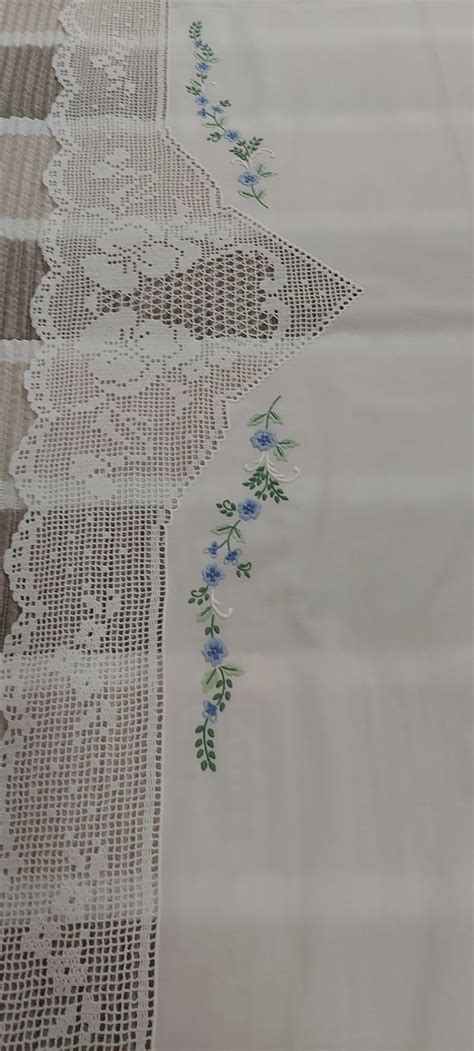 An Embroidered Tablecloth With Blue Flowers And Green Leaves On The