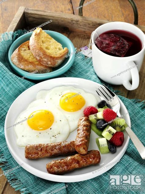 Breakfast Sausage With Fried Eggs And Fruits Served With Toast And