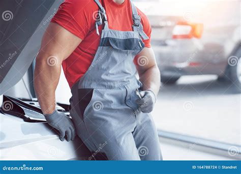 Handsome Young Auto Mechanic in Uniform is Examining Car in Auto ...