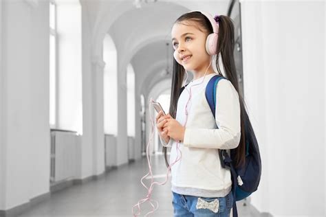 Menina Da Escola Positiva E Inteligente Ouvindo Música Foto Grátis