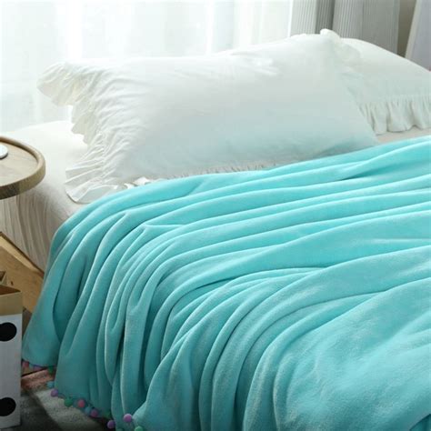 Light Blue Solid Color Fleece Blanket With Pompom On The Bedspring