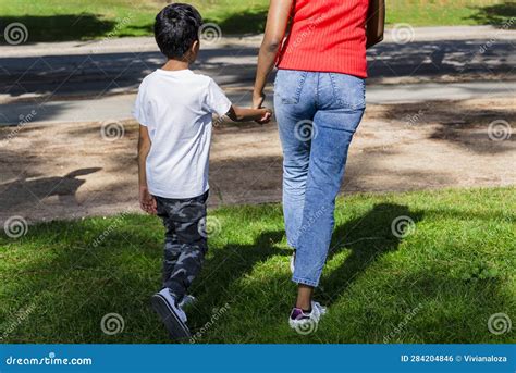 Happy Mother And Son Walking Together Outdoors In A Park Stock Photo