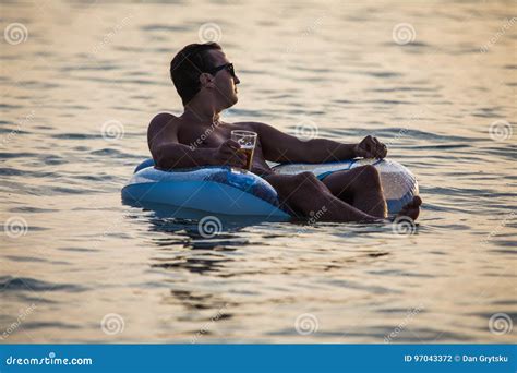 Young Man In Sunglasses Relax In The Ocean Water On Inflatable Ring On