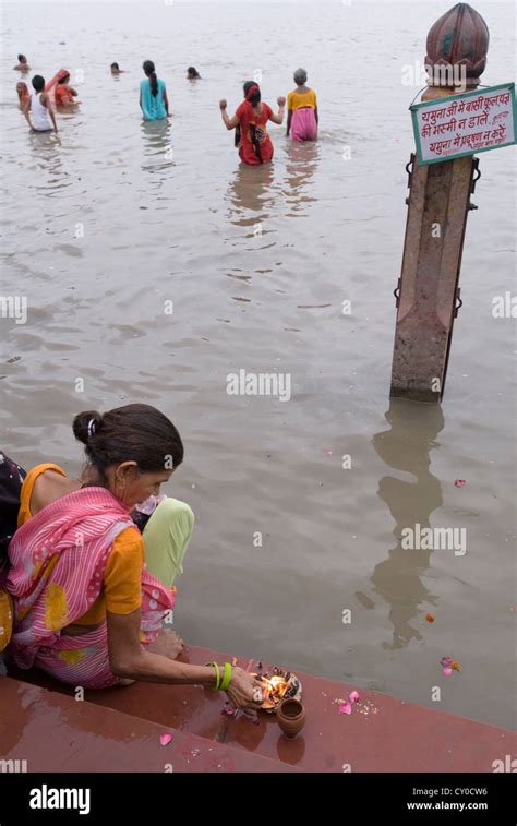 A Hindu Devotee Prepares Offerings To Cast Onto The Yamuna River At