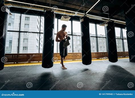 Guy With A Naked Torso Dressed In The Black Shorts Stands Next To The