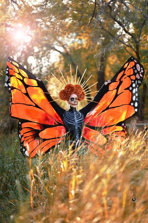 A Woman Dressed Up As A Butterfly With Orange Hair And Makeup Standing