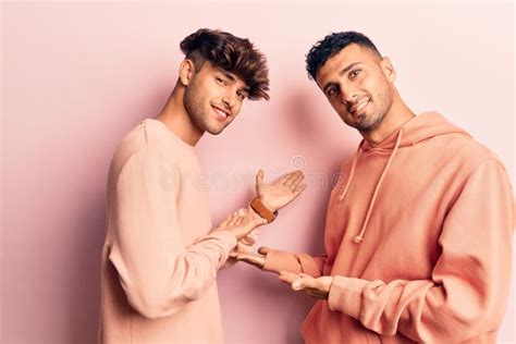 Joven Pareja Gay Con Ropa Casual Invitando A Entrar Sonriendo Natural Con La Mano Abierta Foto