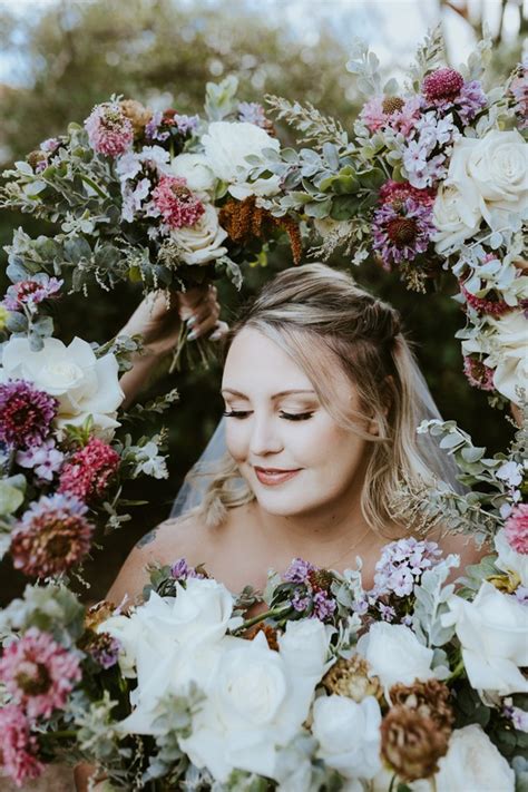 Bride Looking Down Surrounded By Floral Bouquets