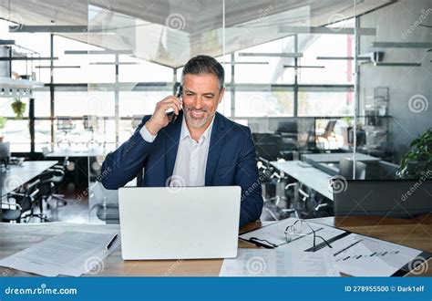 Smiling Mature Business Man Talking On Cell Phone Using Laptop In