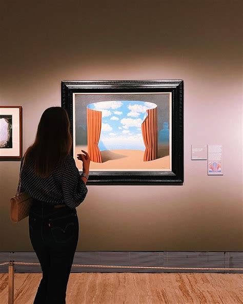 A Woman Is Looking At Paintings On The Wall