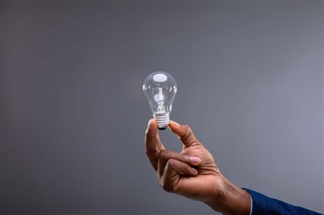 Premium Photo Close Up Of Businessman Holding Light Bulb Against Grey