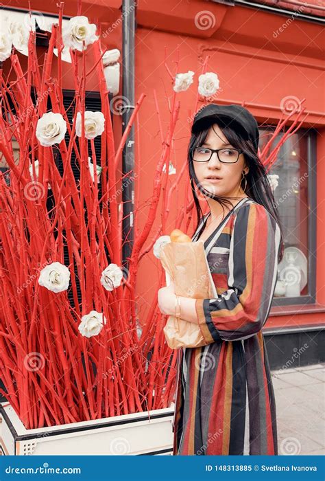 Junge Langhaarige Brunette Frau In Einem Hellen Kleid Und In Einem Hut Gegen Eine Rote Wand