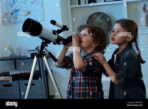 Cute little children using telescope to look at stars in room Stock ...