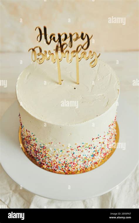 Vertical shot of a cake with a ''happy birthday'' cake topper and sprinkles on a tray Stock ...