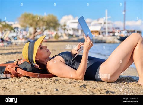 Mature Woman Sunbathing On The Beach In Hat With Laptop Stock Photo Alamy