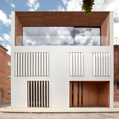 Two White Buildings With Wooden Doors On The Outside And Windows In The