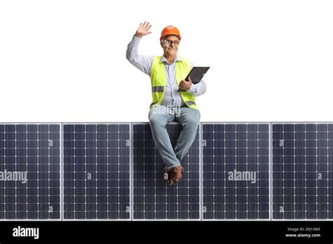 Mature Male Engineer Sitting On A Solar Panel And Waving Isolated On