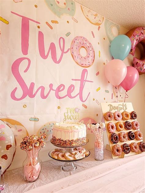 A Table Topped With Cakes And Donuts Covered In Frosting Next To A Sign