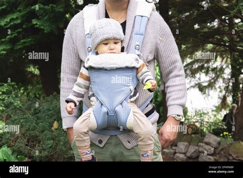 unrecognizable parent carrying  male infant   baby carrier