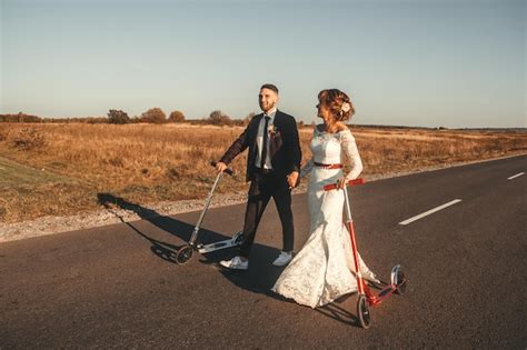 Pareja De Novios Sonriente Montando En Scooters A Lo Largo De La