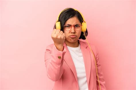 Joven latina escuchando música aislada sobre fondo rosa mostrando el