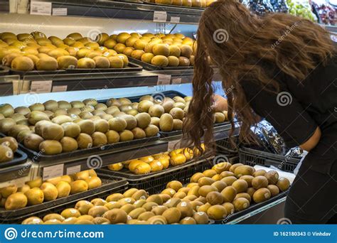 Fresh Healthy Fruits On Shelves In Supermarket With A Woman Choosing