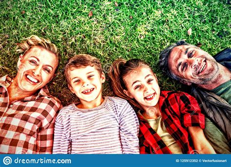 Familia Feliz Que Miente En La Hierba En Parque Foto De Archivo