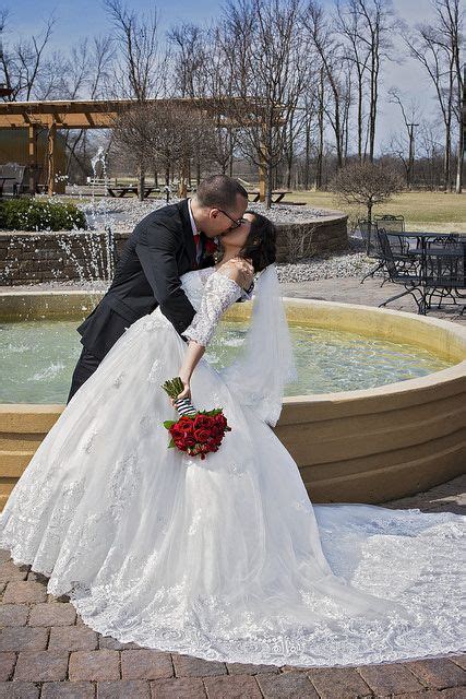 a bride and groom kiss in front of a fountain at their wedding ...