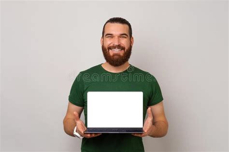 Wide Smiling Bearded Man Is Holding A Laptop And Showing Blank Screen