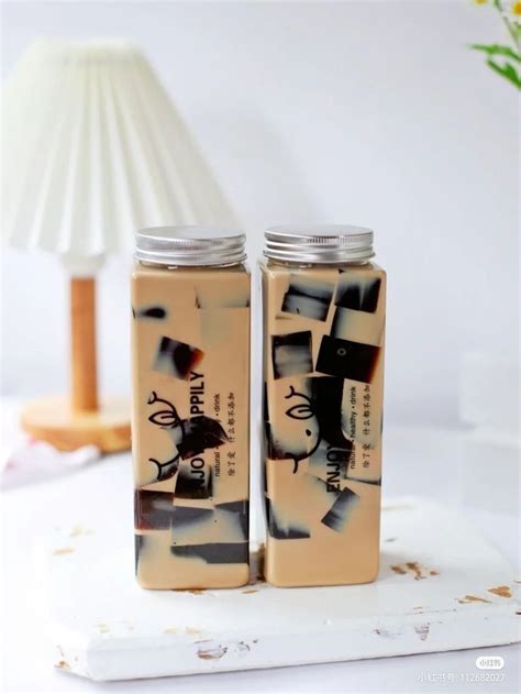 Two Empty Bottles Sitting On Top Of A White Table Next To A Lamp And Vase