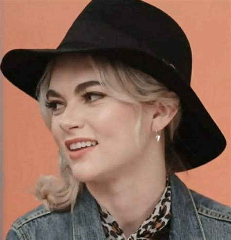 A Woman With Blonde Hair Wearing A Black Hat And Leopard Print Neck Tie