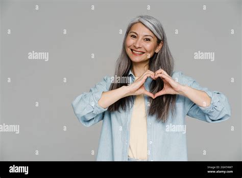 Mature White Haired Woman Smiling And Showing Heart Gesture Isolated