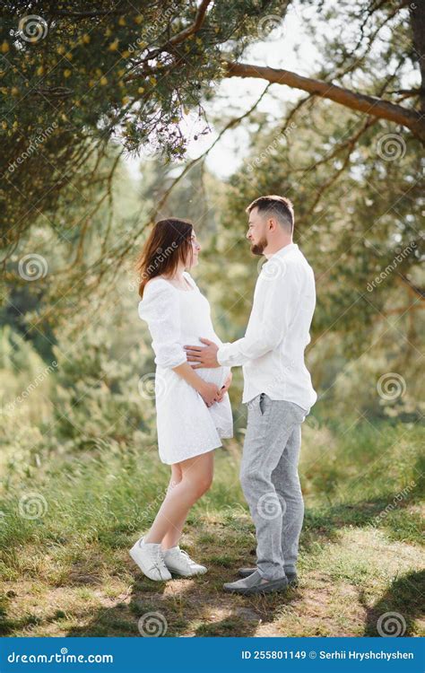 Happy And Young Pregnant Couple Hugging In Nature Stock Image Image