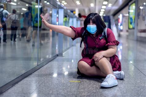 Asian Woman Tourist Wearing A Surgical Masks Sitting On The Floor Of A Train Station Walkway