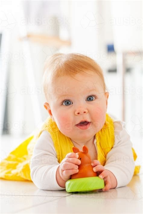 Image Of Young Australian Baby Girl In Yellow Dress Playing With