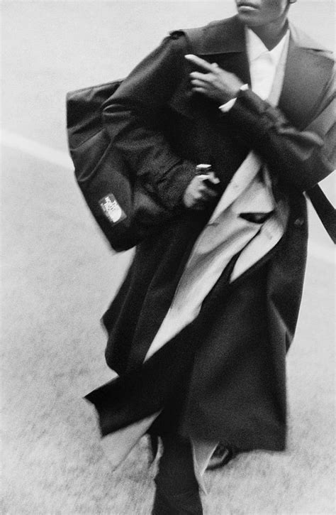 Black And White Photograph Of A Man In A Trench Coat Carrying A Bag On