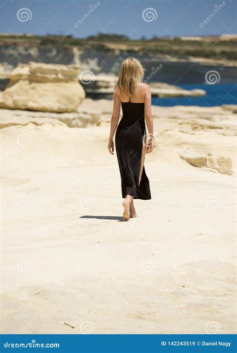 De Mooie Blondevrouw Gaat Naakte Voet In Sexy Lange Kleding Bij Strand