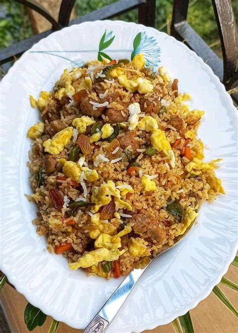 A White Plate Topped With Fried Rice And Veggies Next To A Metal Fork