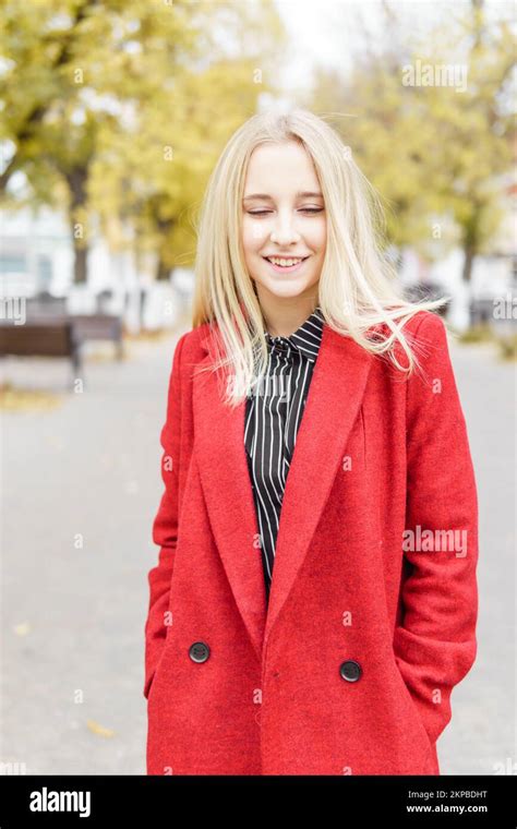 Une jeune femme blonde se promène dans la ville d automne sous un manteau rouge Le concept de