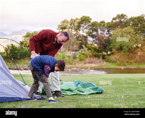 There You Go A Father And Son Setting Up A Tent Together While Camping