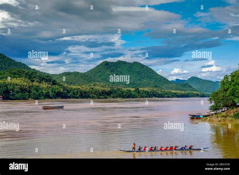 A Traditional Laos Slow Boat Glides Through The Muddy Lower Basin Of