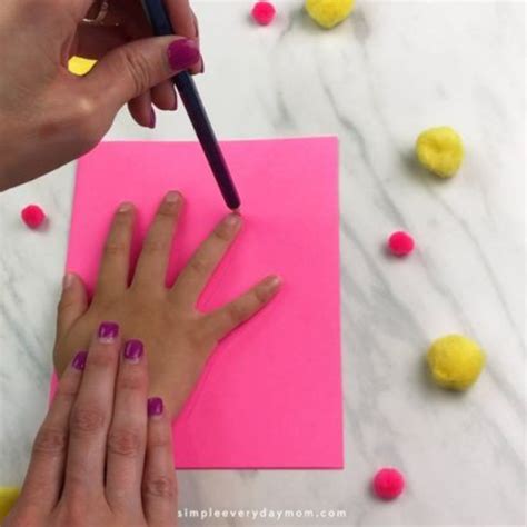 Two Hands With Manicured Nails Are Writing On A Piece Of Pink Paper