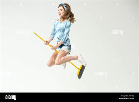 Happy Beautiful Young Woman Flying On Broom On Grey Stock Photo Alamy