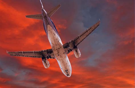 Download Airplane Soaring Through Sunset Sky Wallpaper