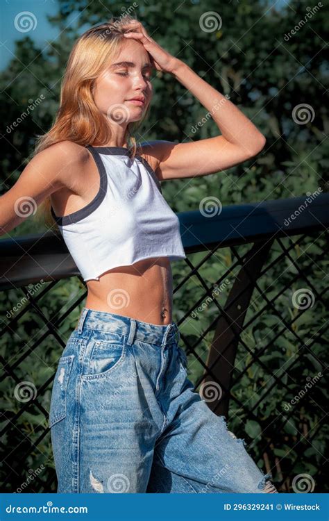 A Young Lady In Jeans And White Crop Top Standing With Her Hands On Her